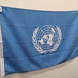 Sininen YK:n lippu kuvattu valkoista seinää vasten.